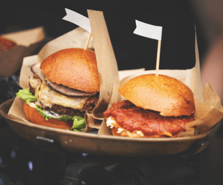 A photograph of two burgers on a plate in a kitchen environment.