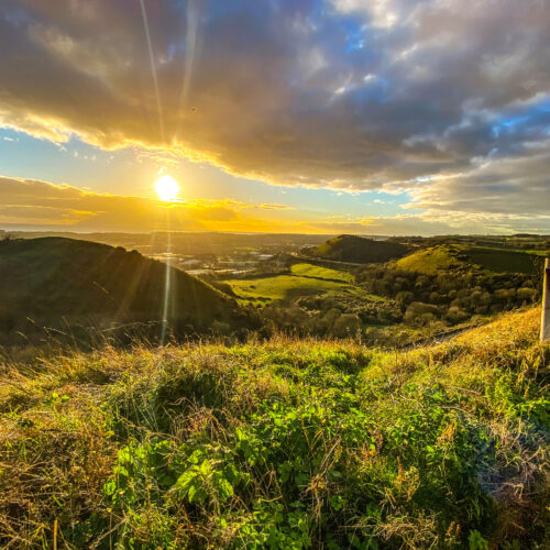 The sun shines on rolling green hills in the north downs