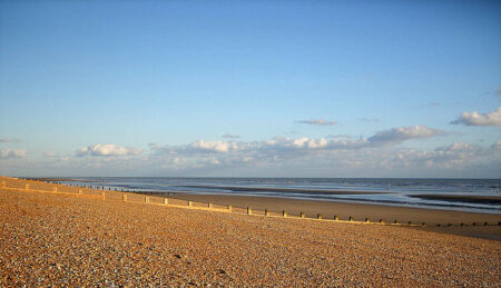 A shingle beach with groynes stretching into the sea