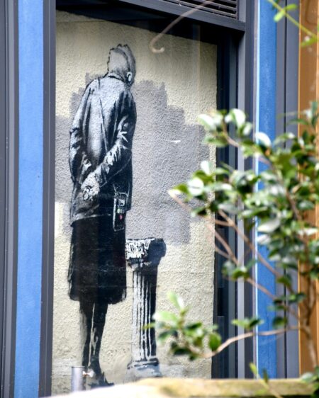 A piece of art depicting the back of an elderly lady looking at a blank pillar