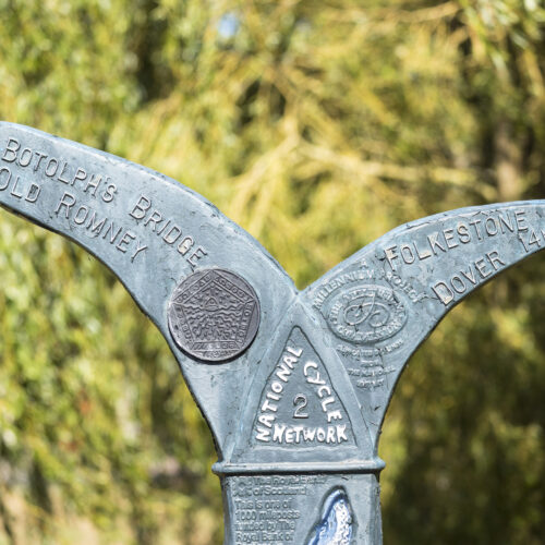 Blue signpost with two curves forking in opposite directions from its top. The middle has a triangle with 'National Cycle Network 2' written.