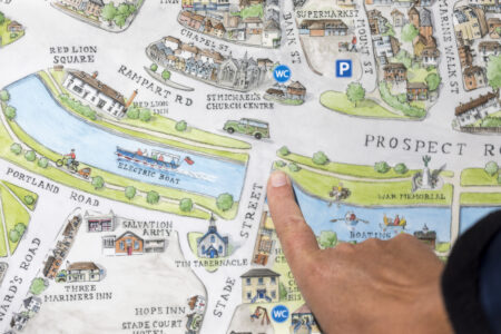 Someone points to the middle of a map of Hythe which has a canal with bridges across it.