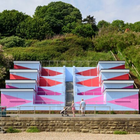 A couple looking up at tiered colourful beachhuts