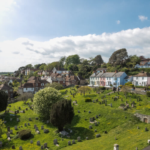 A large green cemetary stretches up a hill to a row of colourful houses