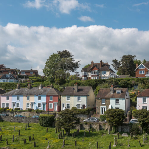 Colourful houses sit next to each other with a cemetery in the foreground