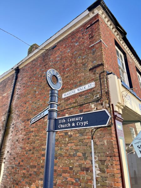 A blue signpost against a brick building